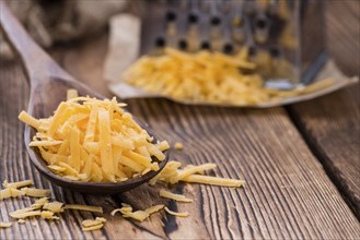 Cheddar Cheese (grated) as close-up shot on an old vintage wooden table