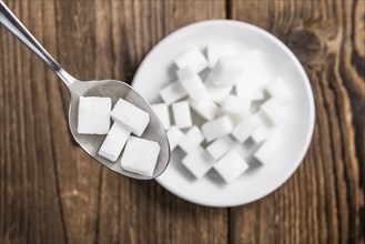 Portion of White Sugar (detailed close-up shot, selective focus) on wooden background