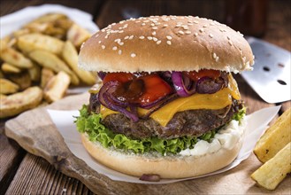 Big fresh made Burger on rustic wooden background (with French Fries)