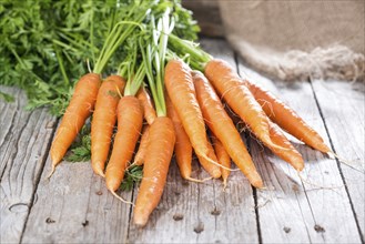 Some fresh Carrots on wooden background (close-up shot)