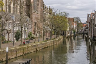 Picturesque scene along a canal with historic buildings, trees and walkway, view of church,