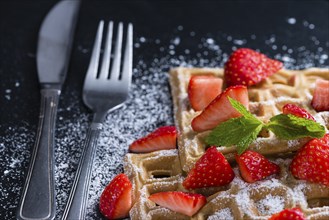 Waffles with some fresh Strawberries (detailed close-up shot) on dark background