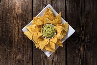 Portion of Nachos (with Guacamole) on wooden background