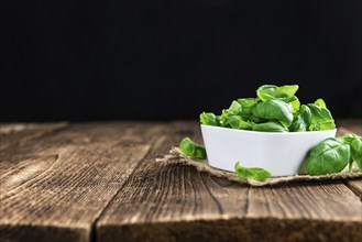 Heap of fresh Basil (selective focus) on an old wooden table (close-up shot)
