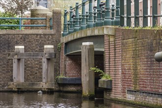 Detail of a brick bridge with green railings spanning a quiet canal, The Hague, Netherlands