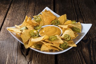 Nachos with Cheese Sauce (close-up shot) on wooden background