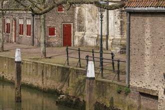Quiet neighbourhood along a canal in front of historic brick buildings with red doors and windows,