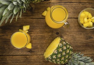 Pineapple Juice as high detailed close-up shot on a vintage wooden table, selective focus