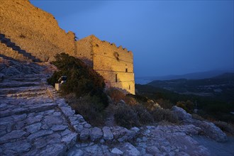 Night shot, Illuminated castle ruins on rocky terrain with a view of the surrounding landscape and