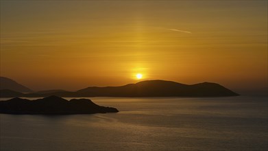 A sunset over the sea, bathing the sky in golden colours and showing tranquil islands in the