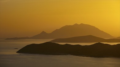 Golden sunset over the sea with silhouetted mountains in the background, Makri Island, Alimia