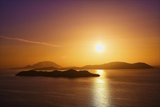 Violet-golden sunset over calm sea and silhouetted islands, Makri Island, Alimia Island, Chalki