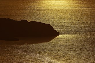 Coastal silhouette in golden light, calm sea reflecting the sunset, Kritinia Castle, St John's