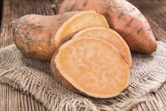 Raw Sweet Potato (detailed close-up shot) on wooden background