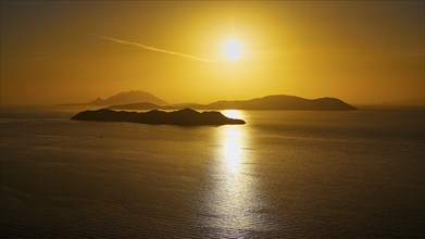 Sunset over calm sea with islands in golden light, Makri Island, Alimia Island, Chalki Island,