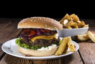 Big fresh made Burger on rustic wooden background (with French Fries)