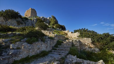 Remains of a castle on a hill with stone steps and vegetation under a clear sky, Kritinia Castle,