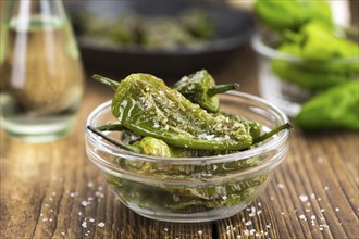 Pimientos de Padron on an old wooden table as detailed close-up shot, selective focus