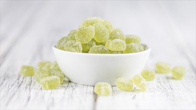 Wooden table with sour gummy candy (apple taste) as detailed close-up shot