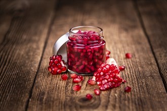 Portion of healthy preserved Pomegranate seeds on an old wooden table (selective focus, close-up