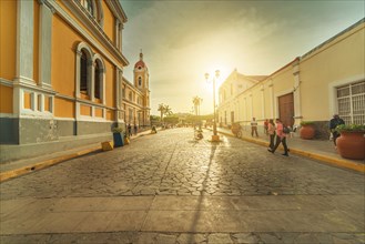 Urban view of people walking through the streets of Granada Cathedral at sunset. Granada, Nicaragua