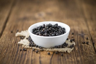 Preserved black Peppercorns on wooden background, selective focus, close-up shot