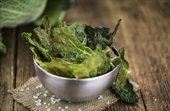 Healthy Savoy Chips on a wooden table as detailed close-up shot (selective focus)