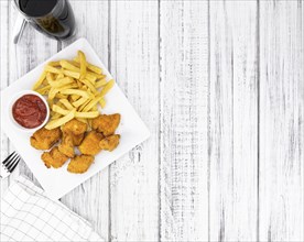 Vintage wooden table with fresh made Chicken Nuggets (close-up shot, selective focus)