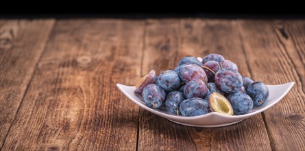 Plums on an old wooden table as detailed close-up shot, selective focus