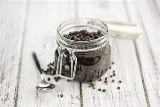 Black Peppercorns preserved on wooden background, selective focus, close-up shot