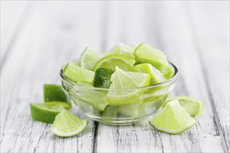 Sliced Limes on an old wooden table as detailed close-up shot (selective focus)