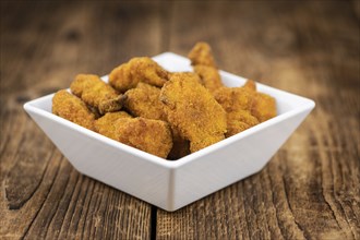 Vintage wooden table with fresh made Chicken Nuggets (close-up shot, selective focus)
