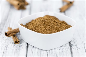 Cinnamon Powder as high detailed close-up shot on a vintage wooden table (selective focus)