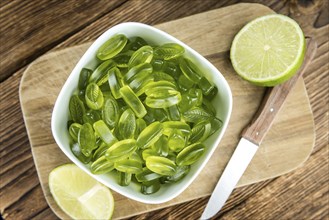 Heap of gummy candy with lime taste on wooden background (selective focus, close-up shot)