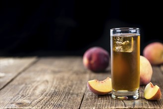 Old wooden table with fresh made tasty peach ice tea (selective focus)