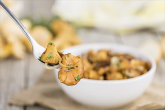 Fried Chanterelles on rustic wooden background as close-up shot