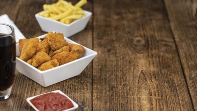Vintage wooden table with fresh made Chicken Nuggets (close-up shot, selective focus)