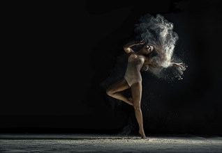 Amazing photo of graceful woman dancing with dust in studio