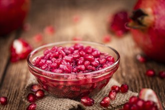 Portion of healthy preserved Pomegranate seeds on an old wooden table (selective focus, close-up