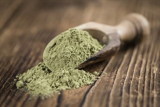 Portion of Stevia leaf powder (detailed close-up shot) on rustic wooden background