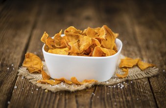 Sweet Potato Chips as high detailed close-up shot on a vintage wooden table, selective focus