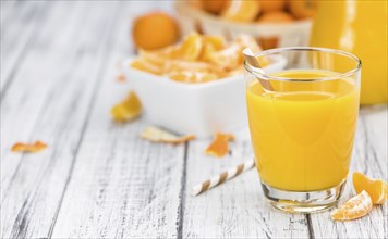 Homemade Tangerine Juice on an old and rustic wooden table (selective focus, close-up shot)