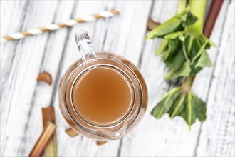 Old wooden table with fresh made Rhubarb Juice as detailed close up shot (selective focus)