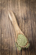 Portion of Stevia leaf powder (detailed close-up shot) on rustic wooden background
