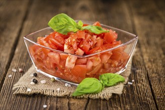 Tomatoes (diced) as high detailed close-up shot on a vintage wooden table (selective focus)