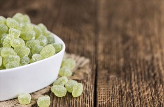 Sour gummy candy (apple taste) on an old wooden table (selective focus)