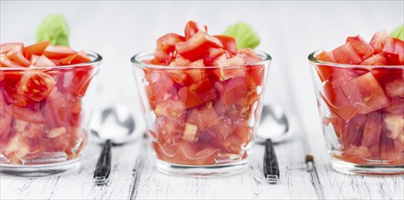 Tomatoes (diced) as high detailed close-up shot on a vintage wooden table (selective focus)