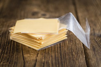 Cheese (sliced) on an old wooden table as detailed close-up shot (selective focus)