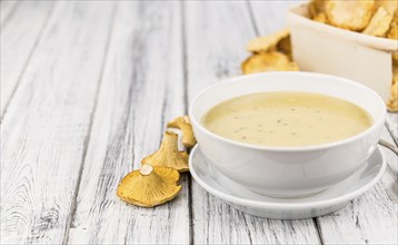 Chanterelle Soup as high detailed close-up shot on a vintage wooden table, selective focus