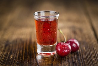 Cherry Liqueur as high detailed close-up shot on a vintage wooden table, selective focus